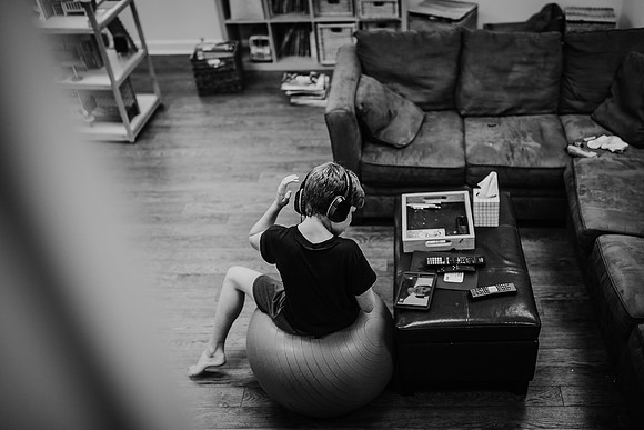 boy wearing a headset and sitting on a exercise ball while looking at his friend on his ipad