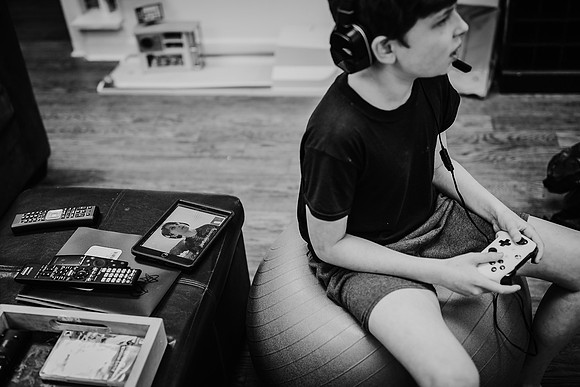 boy playing video game while his friend is on his ipad via facetime