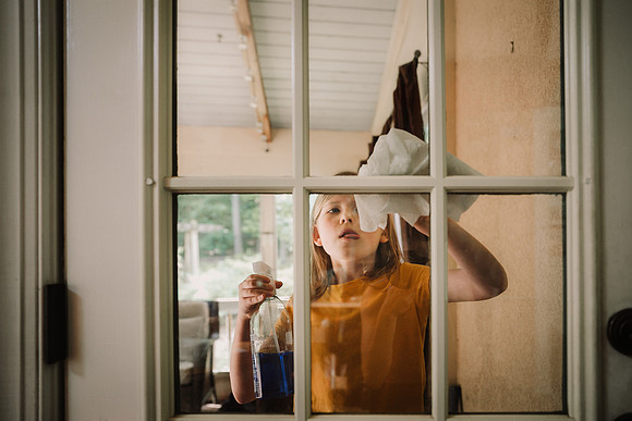 little girl cleaning windows as a chore