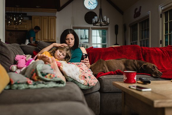 mom snuggled on the couch with her daughter early in the morning