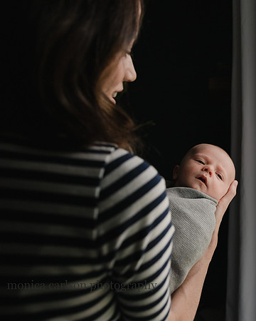 dramatic portrait of a baby being held by his mother by a window