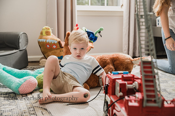serious toddler sitting on the floor of his room among his toys