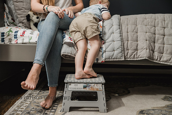 little boy's leg standing on a stool in front of his bed while his sister sits