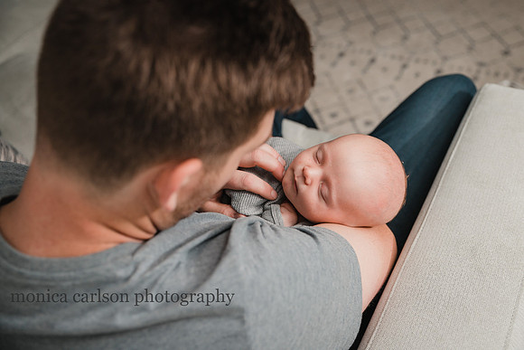 father holding his newborn baby while he sleeps at home