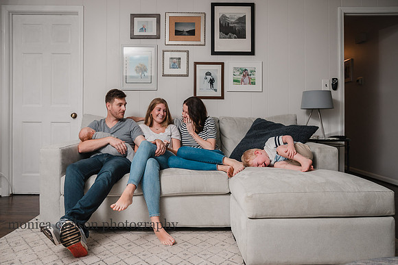 family giggles on the living room couch as a toddler throws a fit