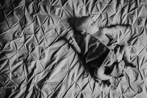 photo from above of a newborn laying on a large bed