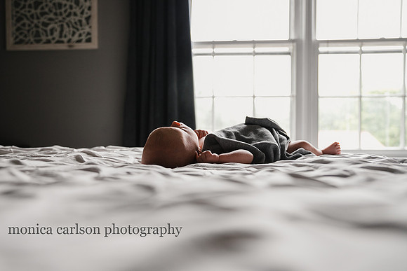 back lit image of a newborn laying his parent bed at home
