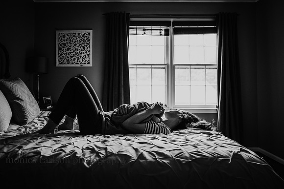 back lit image of a mother laying on her bed with her baby