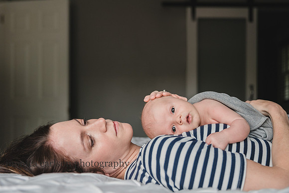 image of a mother laying with her newborn on her chest during a in home photo session