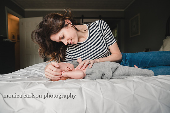 woman laying with her newborn baby on a bed
