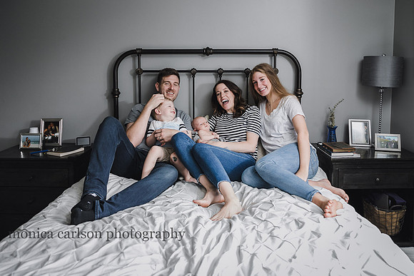 family of six happily laughing together on a bed during a family photography session