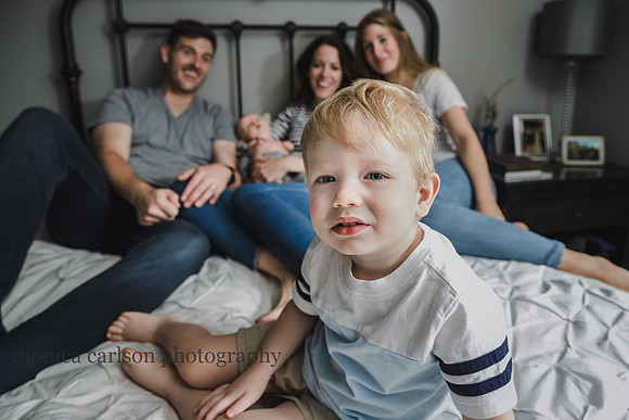 portrait of a blonde boy with his family behind him by monica carlson