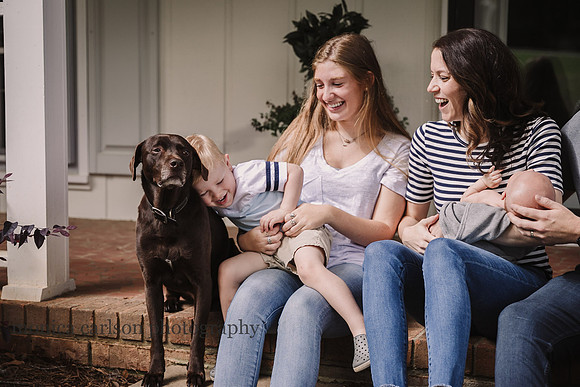 family laughing while their toddler hugs the dog