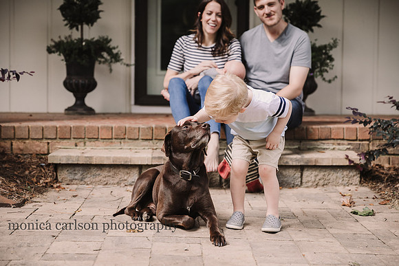 little boy kissing his dog while his parent watch