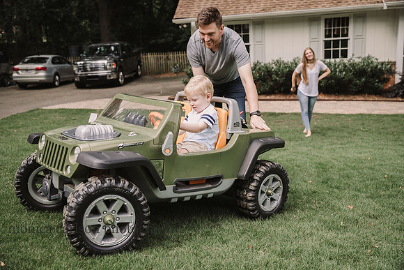 father helping his toddler drive a toy truck