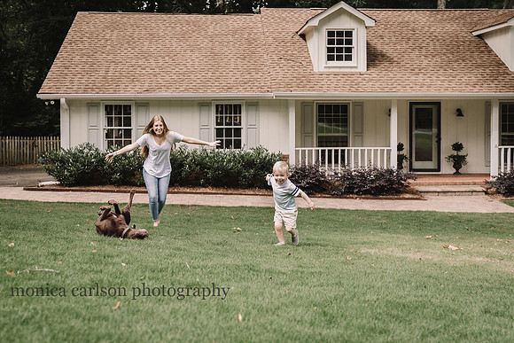 teen girl playing airplane with her little brother while the dog rolls on the lawn