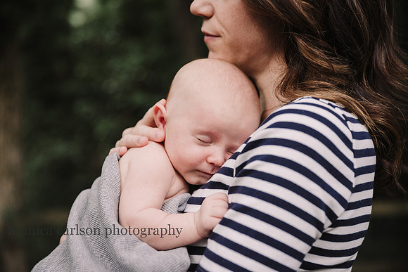 newborn baby boy being held by his mother outside their home