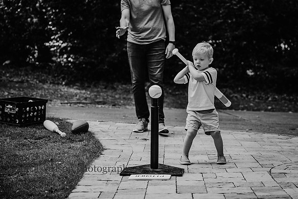 toddler playing t-ball outside with his father