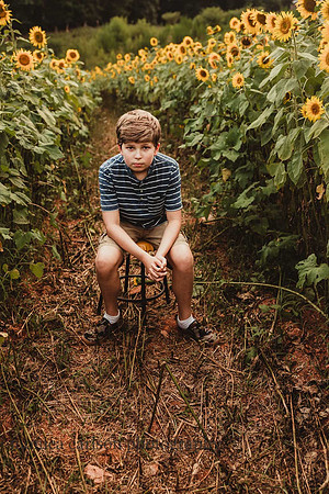teen boy looks serious on a field of sunflowers