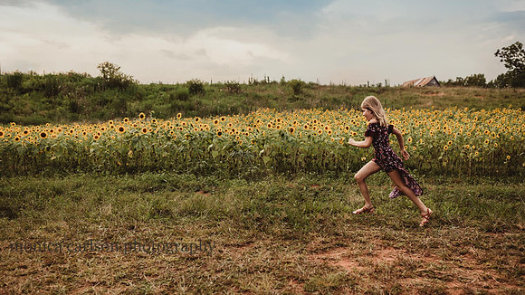 girl runs by a sunflower field at sunset