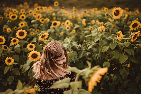 girl twirls her hair surrounded by sunflowers