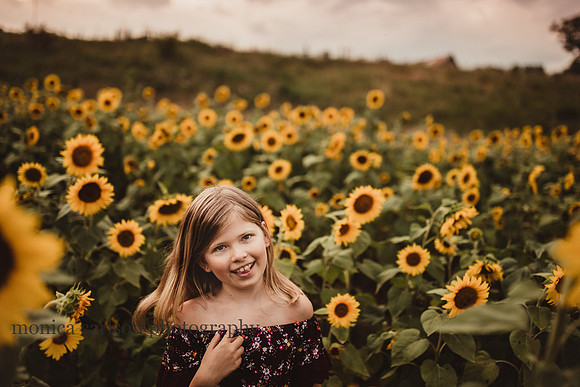 girl smiles at the camera during a photo session on a sunflower field in Cumming, Georgia