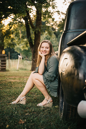 teen girl sitting in the tire wheel of a truck during a senior photo session
