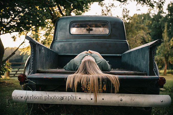 teen aged girl laying on a her back on the back of a truck