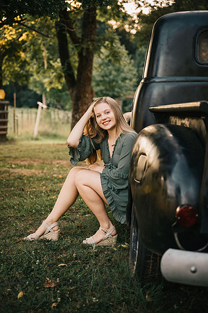 senior brushing her hair from her face while sitting in a truck by monica carlson photography