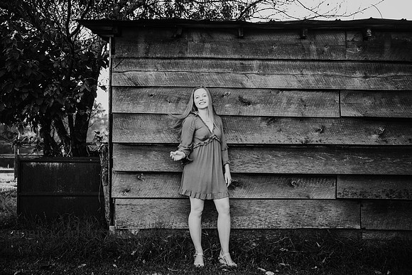 black and white photo of a teenager standing against a barn