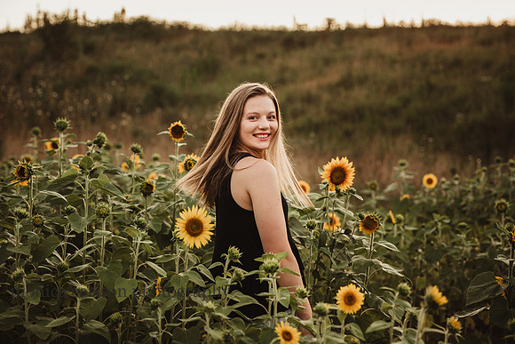 happy teenager looking over her shoulder in a field of sunflowers