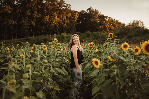 a teenage girl spinning in a sunflower field during her senior photo session