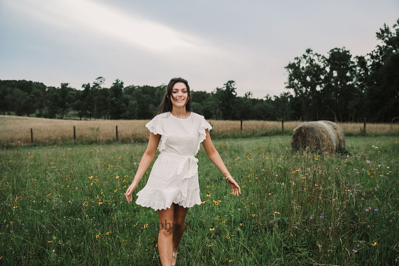 High school senior struts across a flower flower field during a photo session with monica carlson