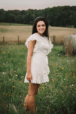 High school senior standing on a flower field on a farm