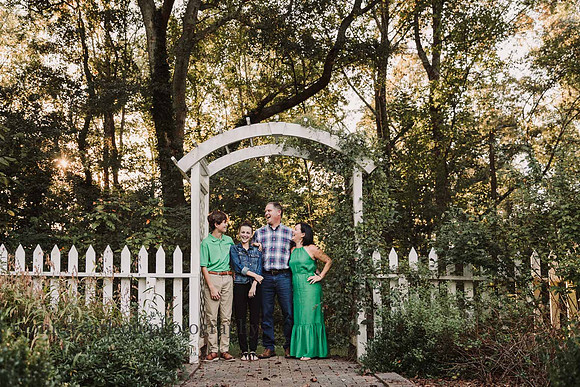 back lit image of family of four laughing together during a family photo session