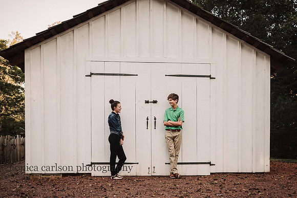 teen aged siblings bonding while standing in front of a barn in Roswell, GA