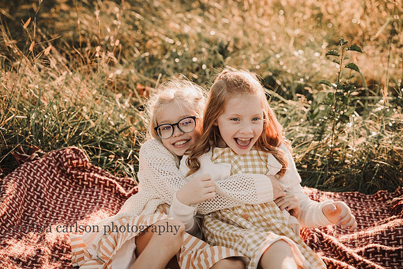 two elementary aged girls cuddling on a blanket during a family photo session