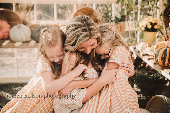 blonde and red haired girls hugging their mother during a greenhouse session
