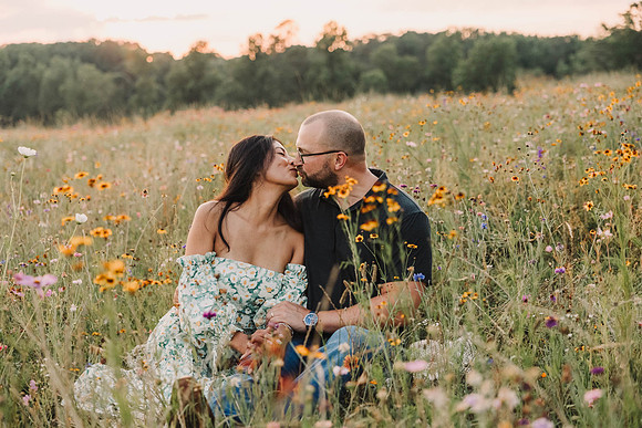 Man and woman kissing while sitting in a wildflower field
