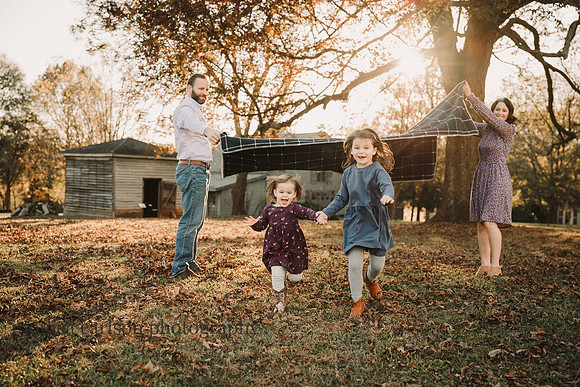 girls running underr a blanket their parents are waving in Roswell, GA