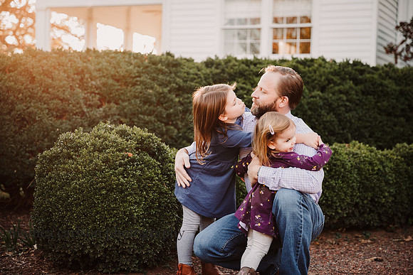 father embracing his young daughters by monica carlson photography