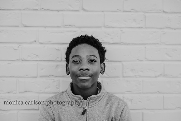 portrait of a african american teenage boy in front of a brick wall