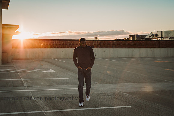 older teen boy walking on a parking lot roof at sunset