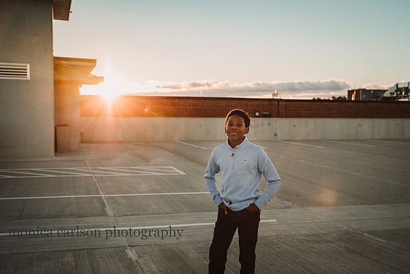 portrait of a african american boy on a roof top parking lot at sunset