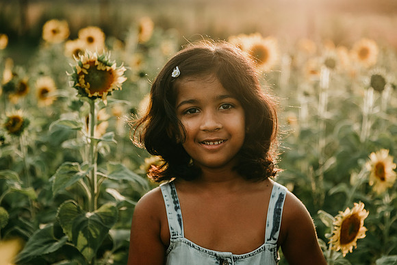 portrait of a young indian girl standing on a sunflwower by monica carlson photography