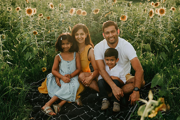 Indian family of four sitting in a sunflower field on prospect farms