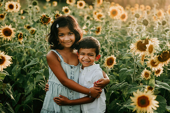 young indian siblings look happy on a sunflower field