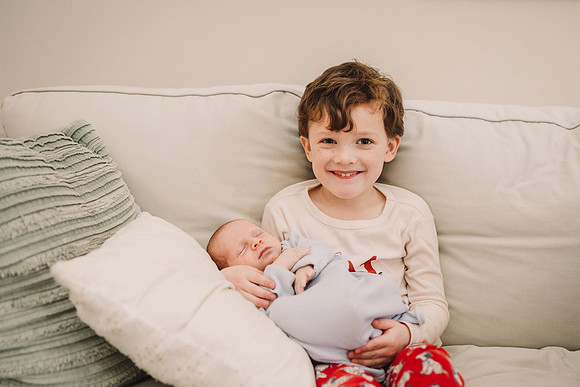 Happy boy holds baby brother