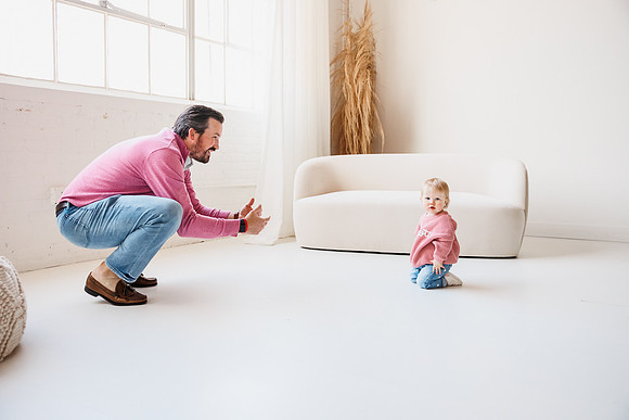 dad encourages young daughter to crawl to him