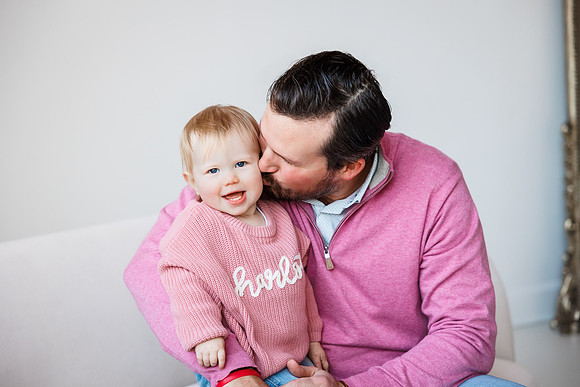 dad kisses his young daughter cheeks